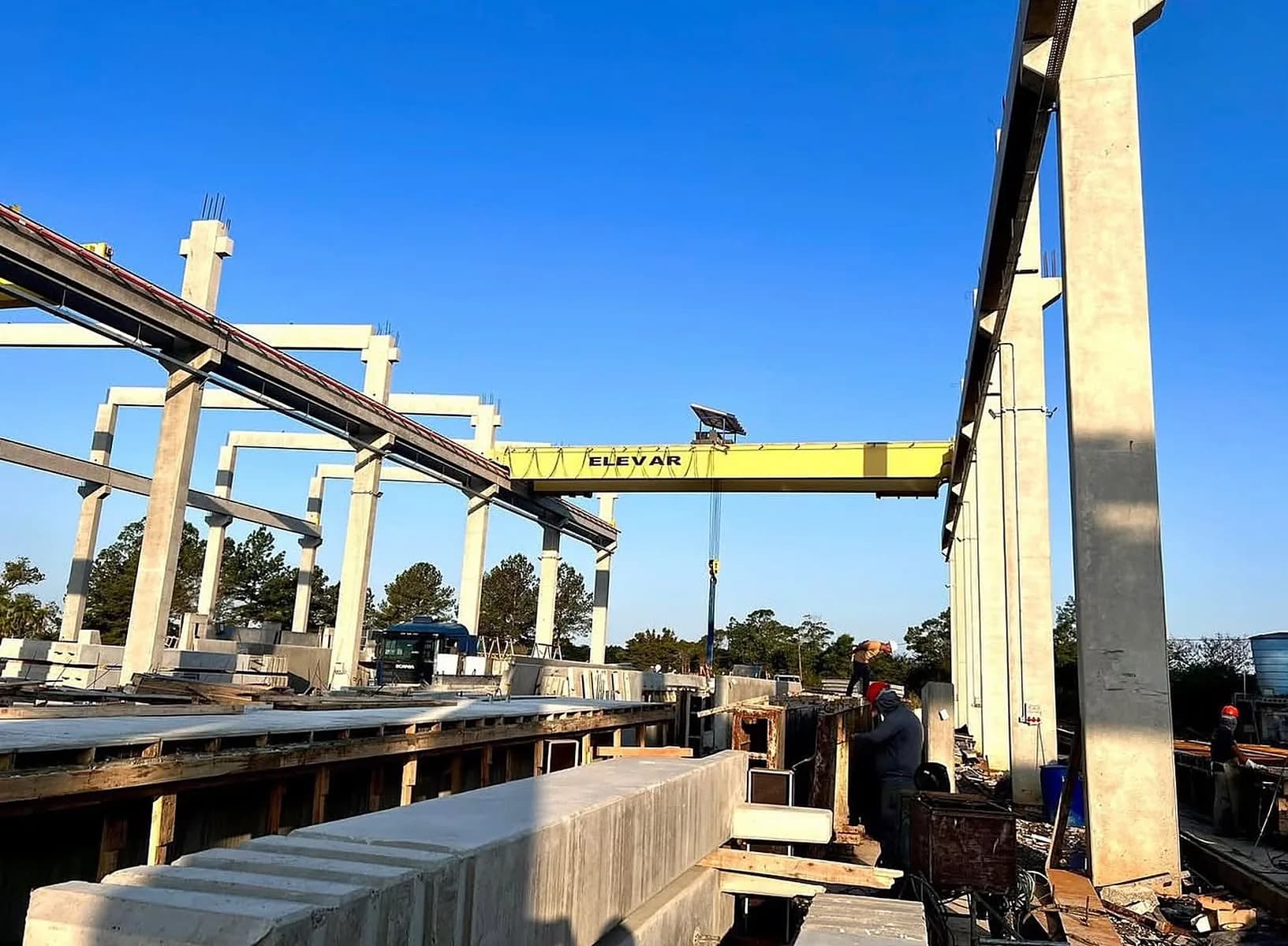 Ponte rolante Elevar com viga amarela sobre pilares de concreto pré-moldado em pátio de produção a céu aberto